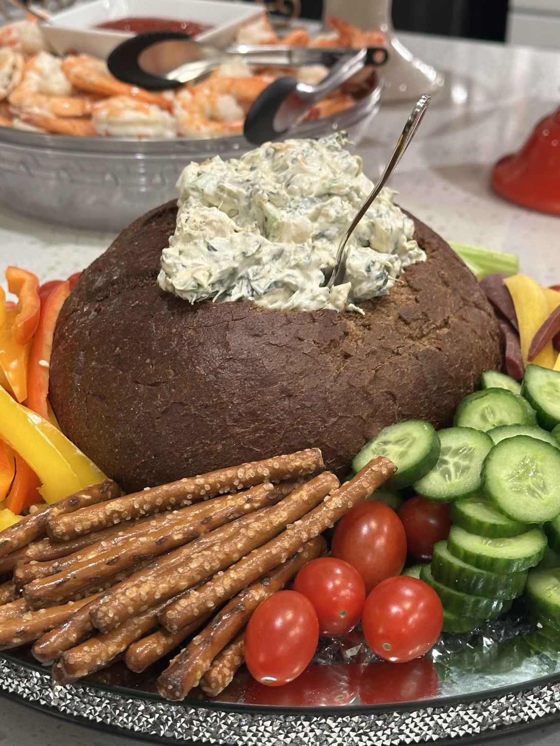 Spinach dip in a pumpernickel bread bowl with crudités