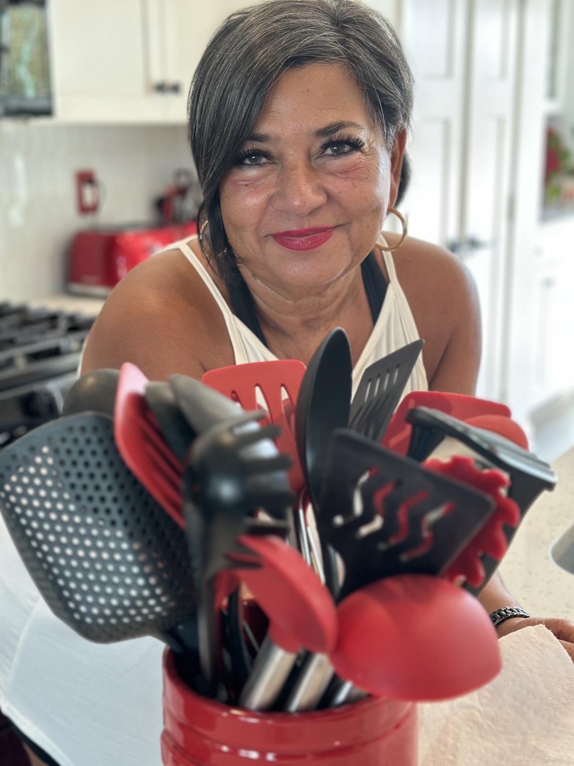 Edie in her kitchen holding a crock of utensils